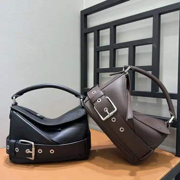 Two leather shoulder bags in black and brown on a wooden table