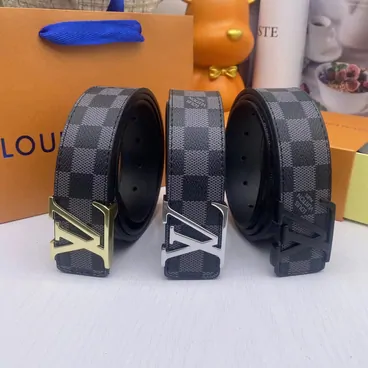 Checked leather belts with metal buckles beside an orange box